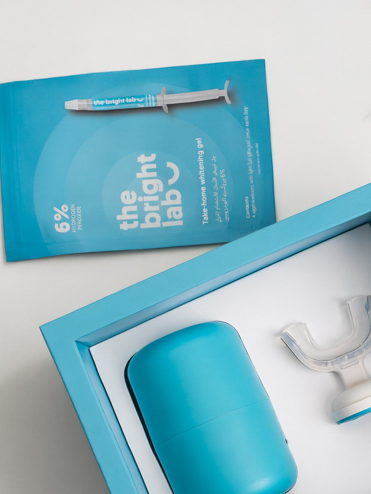 The Bright Lab 6% take-home whitening gel refill sachet with a 3g gel applicator, resting beside the Whitening System case