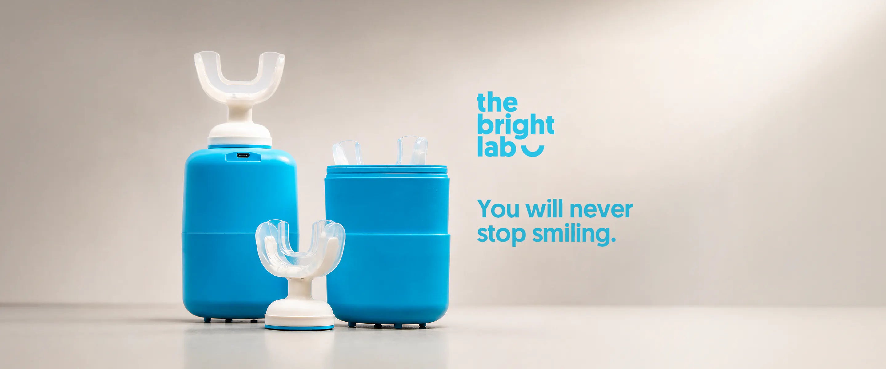 The Bright Lab applicator on its charging base beside the open case, with the wordmark: you will never stop smiling